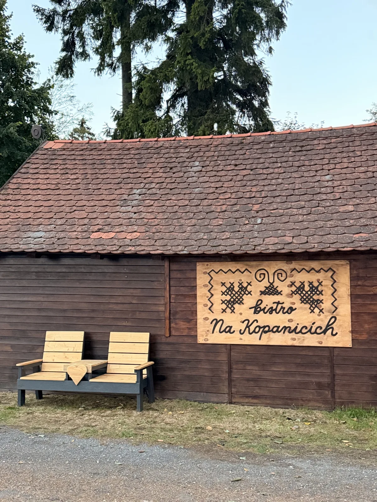 Dřevěná stavba bistra Na Kopanicích s vyřezávanou cedulí a lavičkou se srdcem